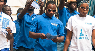 A group of people representing the Sama Sama latrine business in Ghana walk in a parade.