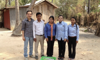 A group of people pose behind a Super Tunsai water filter product.