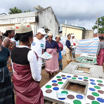 A crowd is gathered around four latrine slab prototypes.