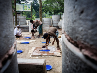 Un producteur de latrines sculptant une dalle de latrines.